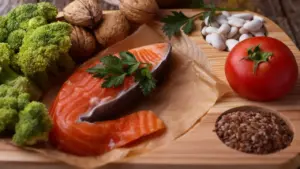 Alimenti sani come salmone, broccoli, noci, pomodoro, fagioli e semi su un tagliere