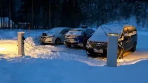 Auto elettriche innevate in ricarica presso stazioni di ricarica in un paesaggio invernale norvegese