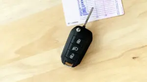 Chiave elettronica per auto e una patente su un tavolo in legno chiaro