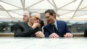 Due uomini in abiti formali parlano in modo confidenziale seduti a un tavolo