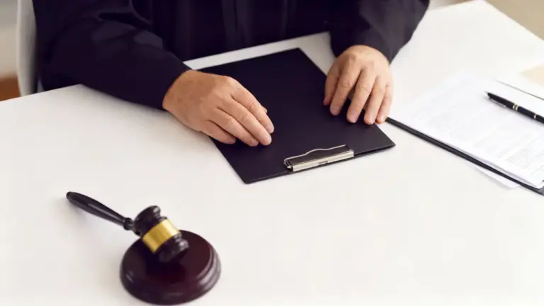 Persona seduta con toga davanti a documenti legali e martelletto su scrivania