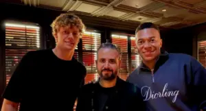 Tre persone posano insieme all'interno di un ristorante elegante con luci soffuse.