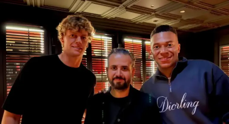 Tre persone posano insieme all'interno di un ristorante elegante con luci soffuse.