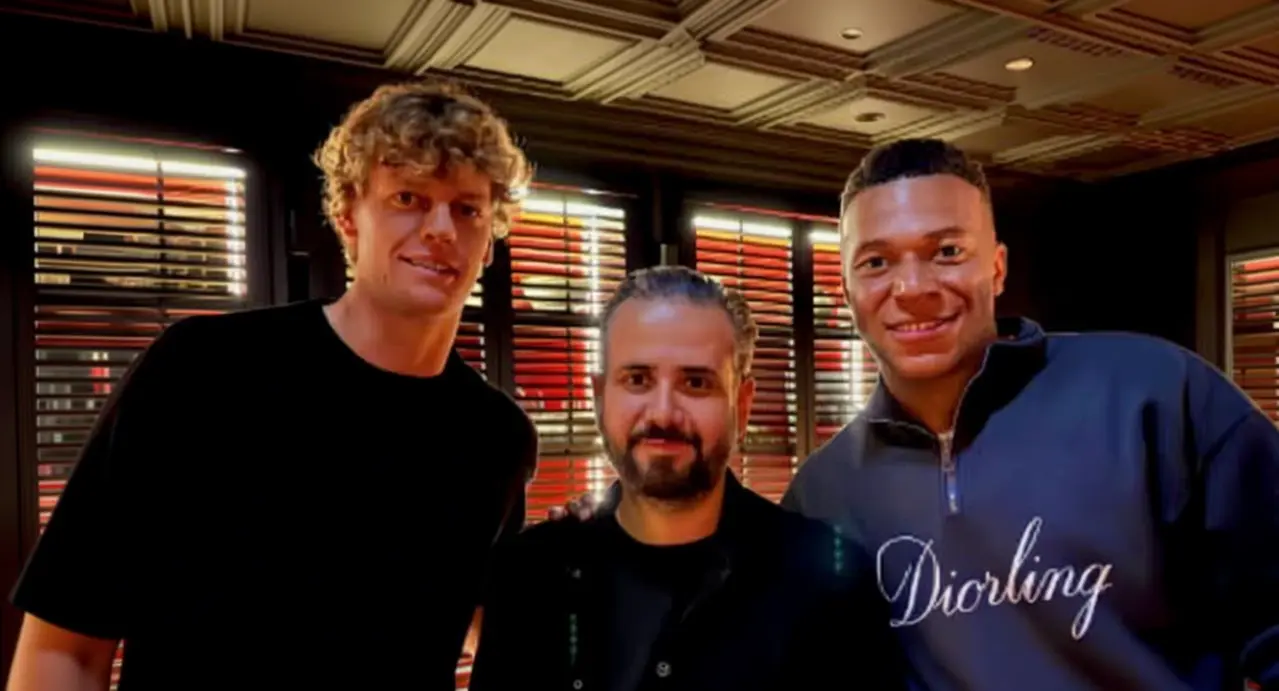 Tre persone posano insieme all'interno di un ristorante elegante con luci soffuse.