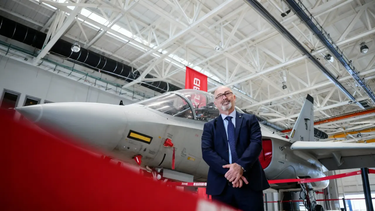 Persona in posa accanto a un aereo militare in un hangar industriale