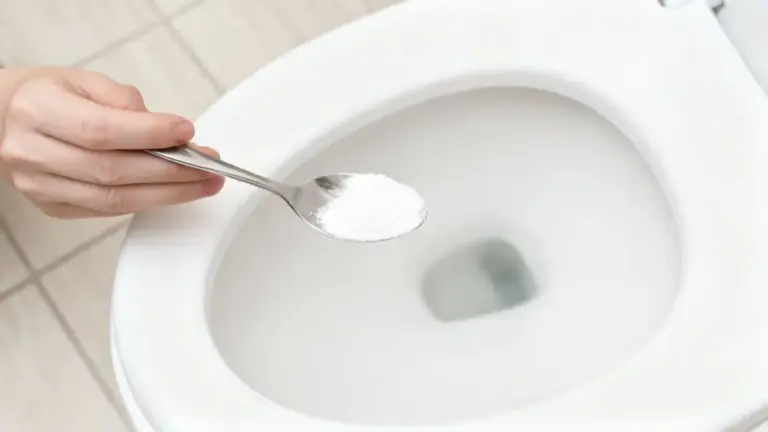 Mano che versa del bicarbonato nel water con un cucchiaio