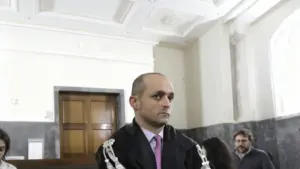 Un uomo in toga in un'aula di tribunale con altre persone sullo sfondo