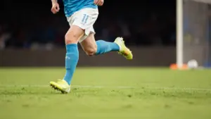 Un calciatore in divisa azzurra corre in campo durante una partita