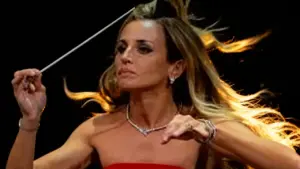 Direttrice d'orchestra in abito rosso sul palco durante una performance teatrale