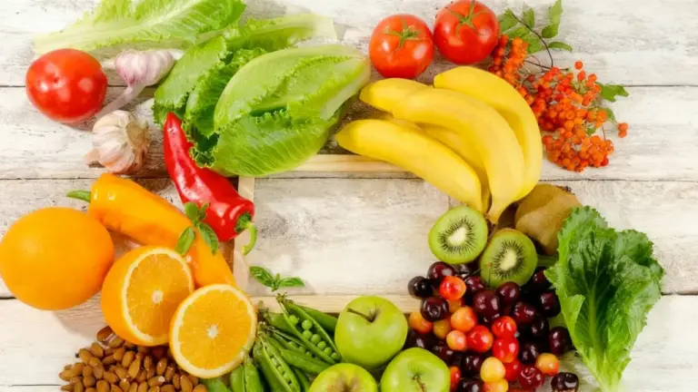 Varietà di frutta e verdura fresca disposte a forma di lettera C su sfondo chiaro