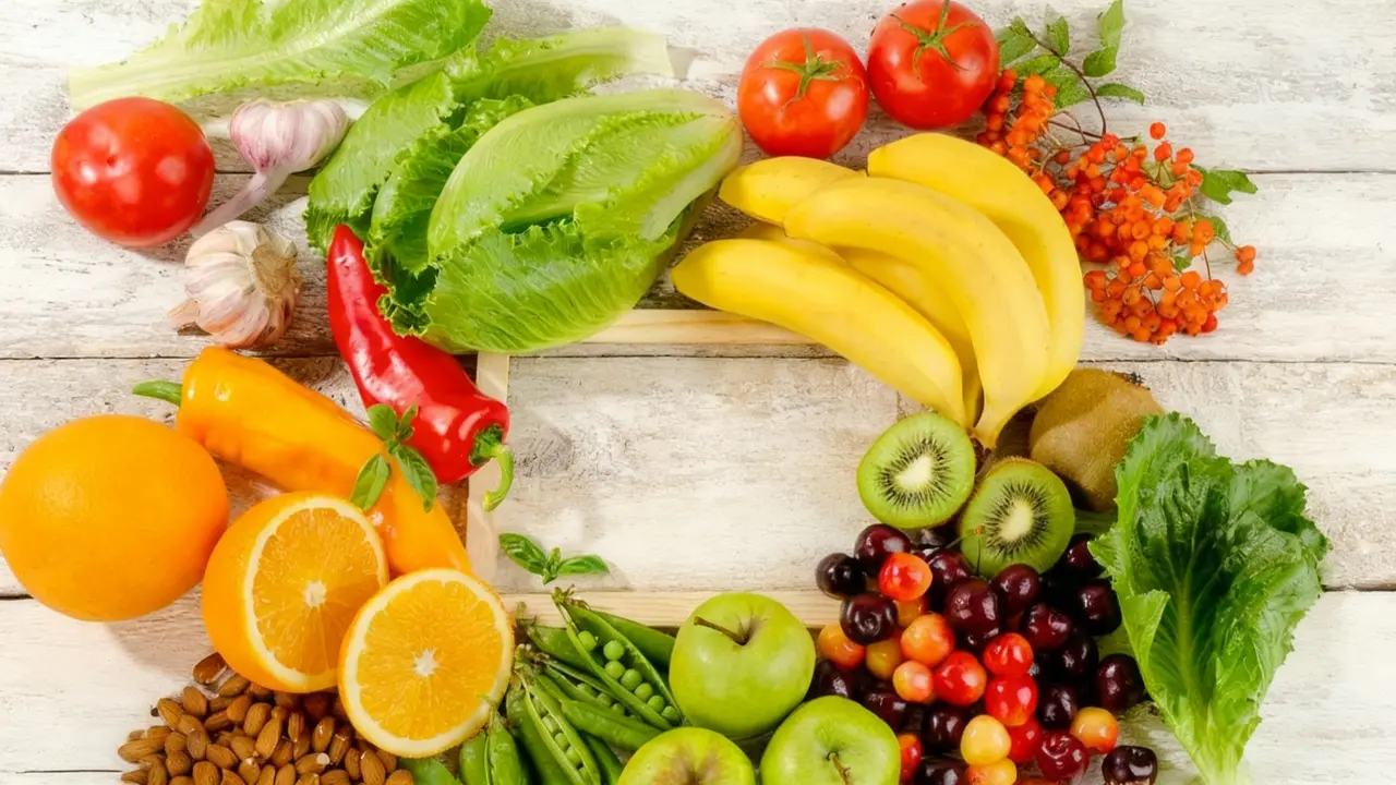 Varietà di frutta e verdura fresca disposte a forma di lettera C su sfondo chiaro