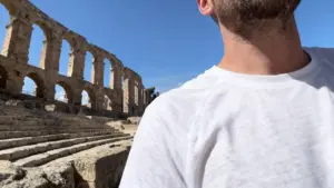 Rovine di un antico anfiteatro con archi in pietra e gradinate sotto un cielo azzurro