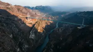 Ponte sospeso tra due montagne sopra una valle con fiume in Cina