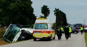 Ambulanza e forze dell'ordine sulla scena di un incidente stradale con un autobus ribaltato