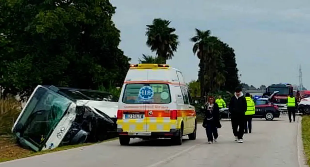 Ambulanza e forze dell'ordine sulla scena di un incidente stradale con un autobus ribaltato