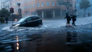 Auto e due persone camminano in una strada allagata durante una forte pioggia