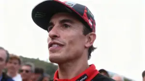 Un uomo con cappellino da corsa sorride tra la folla durante un evento MotoGP
