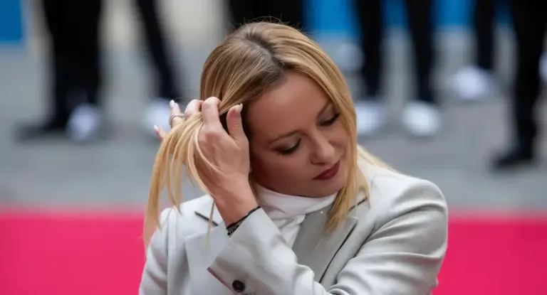 Una donna in abito chiaro si sistema i capelli durante un evento ufficiale