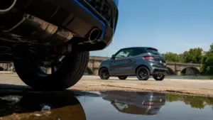 Minicar Ligier JS50 grigia parcheggiata vicino a un fiume con un ponte sullo sfondo