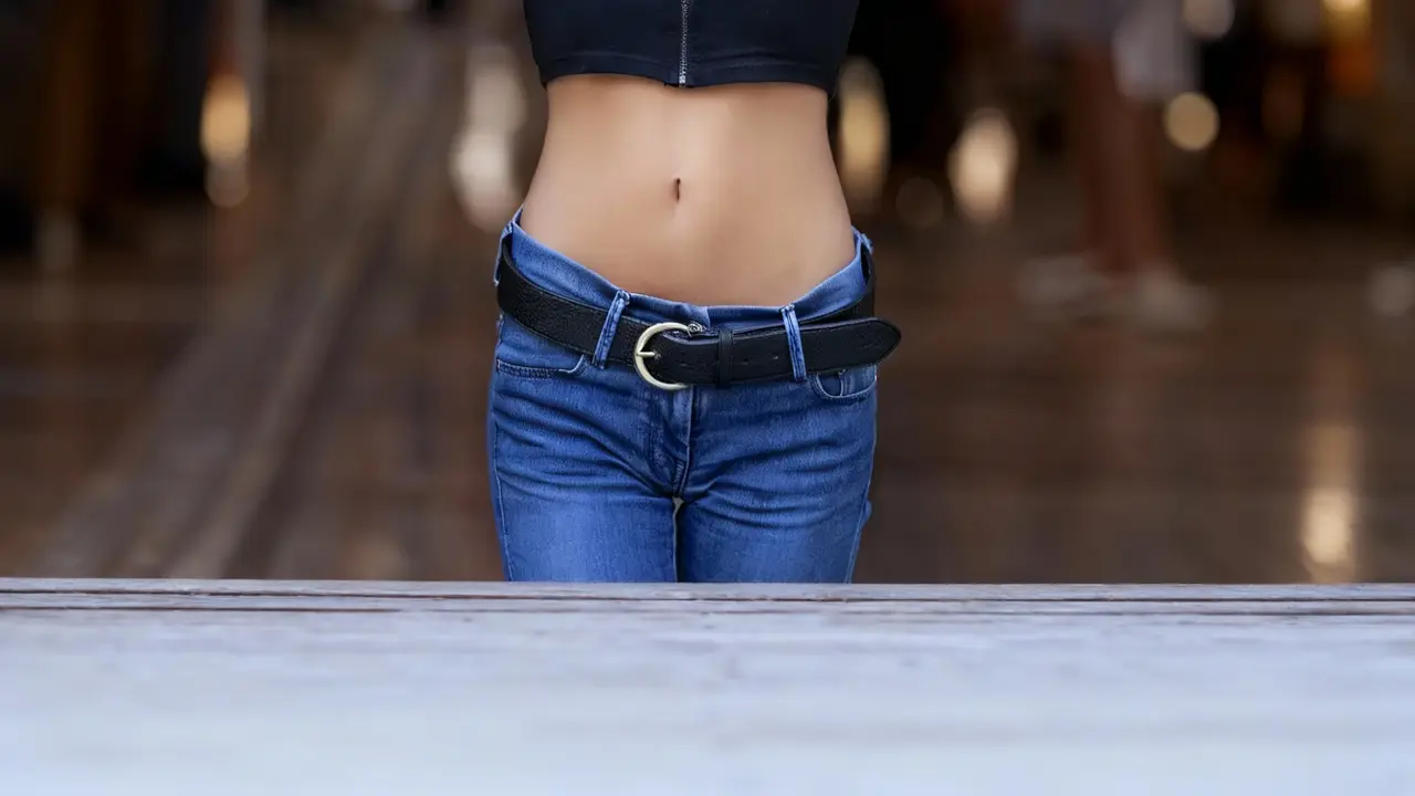 Vista ravvicinata dell'addome piatto di una persona con jeans e cintura nera