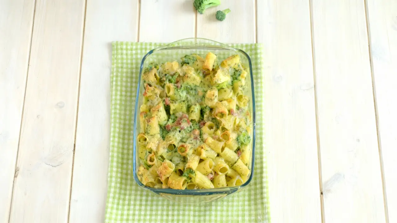 Teglia di pasta al forno con broccoli su tovaglietta verde a quadretti