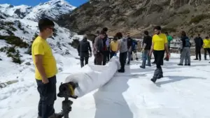 Gruppo di persone su un pendio innevato che rimuove grandi teli bianchi
