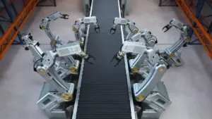 Bracci robotici industriali operano su un nastro trasportatore in un magazzino automatizzato