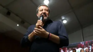 Una persona parla al microfono durante un evento politico al chiuso