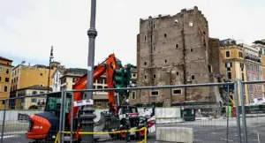 Torre antica circondata da recinzioni e macchinari da cantiere in un contesto urbano