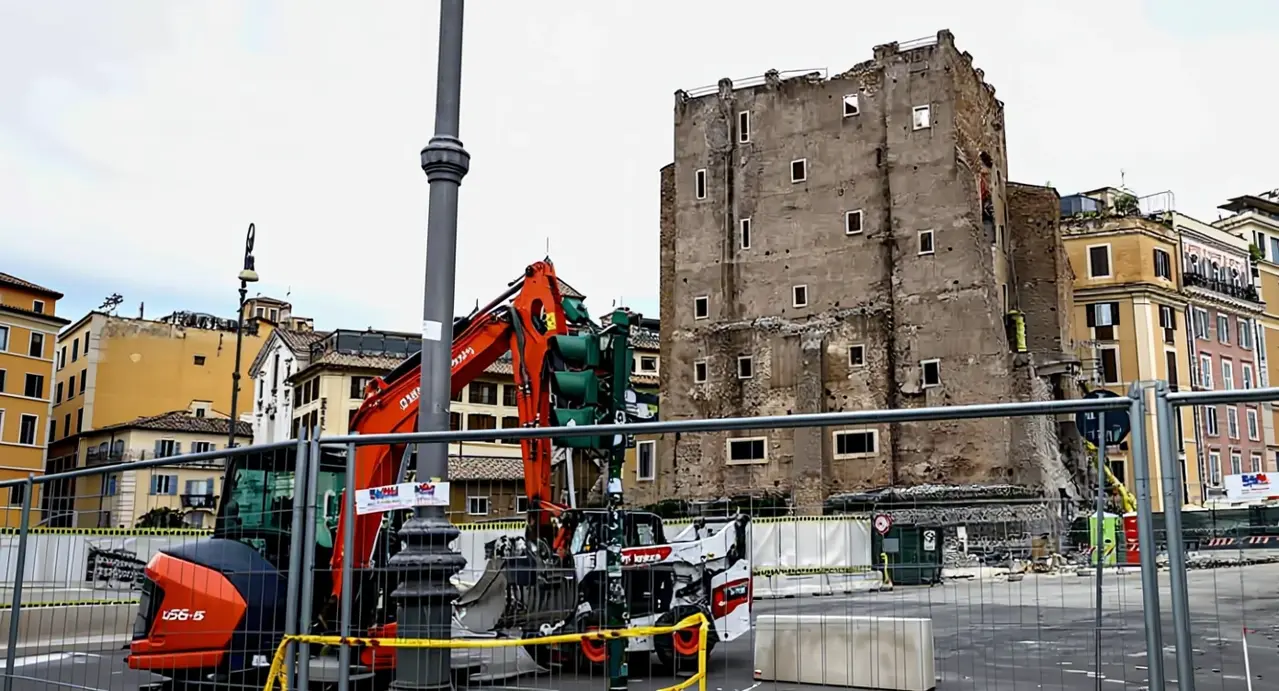 Torre antica circondata da recinzioni e macchinari da cantiere in un contesto urbano