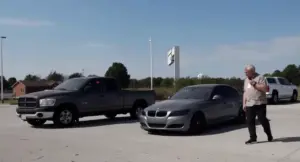 Parcheggio con auto ferme e una persona che cammina vicino a un'auto grigia