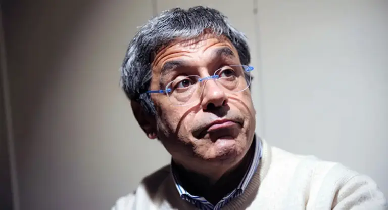 Un uomo con occhiali trasparenti e capelli grigi in un ambiente interno