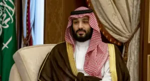 Un uomo in abiti tradizionali sauditi seduto su una poltrona in un ambiente formale