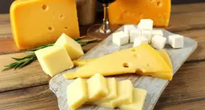 Varie tipologie di formaggi su un tagliere di legno.