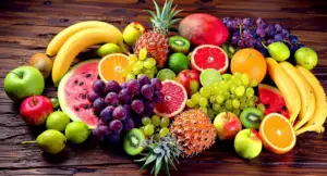 Varietà di frutta fresca su un tavolo di legno, tra cui ananas, uva, arance e kiwi