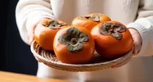 Cachi freschi in un cesto di vimini tenuto da una persona