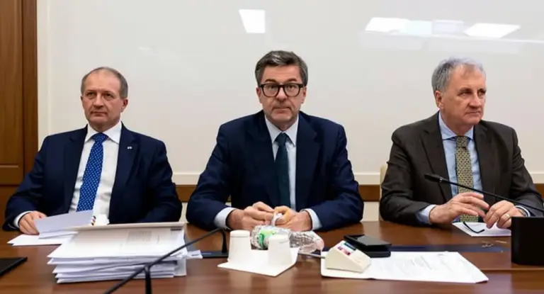 Tre uomini in giacca e cravatta seduti a un tavolo durante un incontro ufficiale