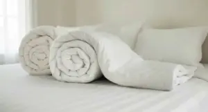 Due piumoni bianchi arrotolati su un letto con lenzuola bianche