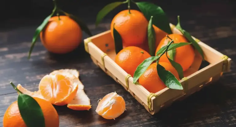 Cestino di mandarini freschi con foglie verdi su tavolo di legno