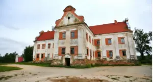 Edificio storico con facciata deteriorata e tetto rosso in mezzo alla campagna