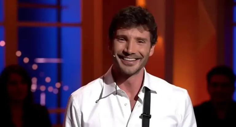 Un uomo sorridente con microfono ad archetto nello studio di un programma televisivo