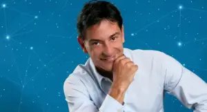 Un uomo sorride con la mano sul mento su sfondo di costellazioni zodiacali