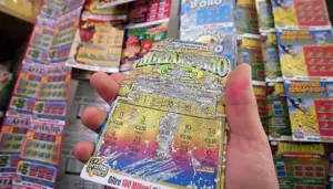 Una mano tiene un gratta e vinci parzialmente grattato in un punto vendita.