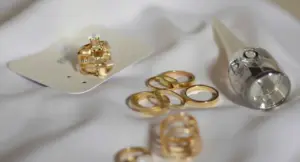 Anelli e gioielli d'oro usati appoggiati su tessuto chiaro con uno strumento da valutazione
