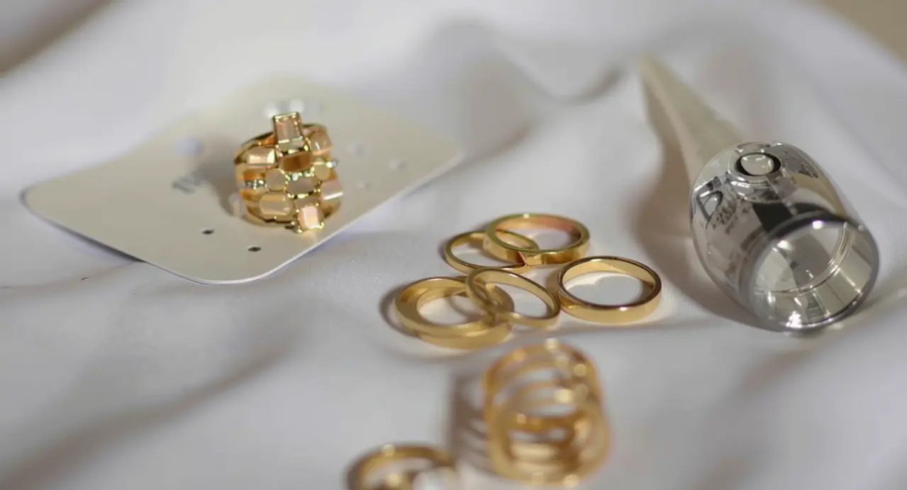 Anelli e gioielli d'oro usati appoggiati su tessuto chiaro con uno strumento da valutazione